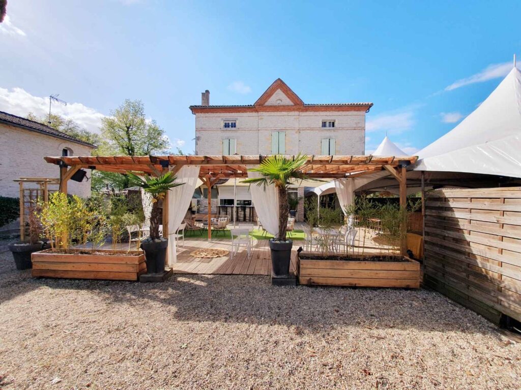 Façade du manoir du Domaine du Baraillot avec pergola et terrasse aménagée